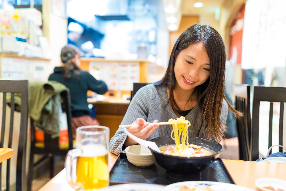 frau-geniesst-ramen-mit-einem-bier-in-einer-authentischen-japanischen-ramenbar