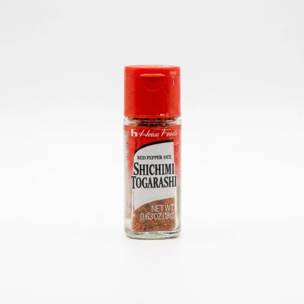 House Foods Shichimi Togarashi, eine japanische 7-Gewürz-Mischung, in einer transparenten Glasflasche mit rotem Streudeckel. Das scharfe Chilipulver ist für authentische asiatische Gerichte wie Ramen oder Sushi.