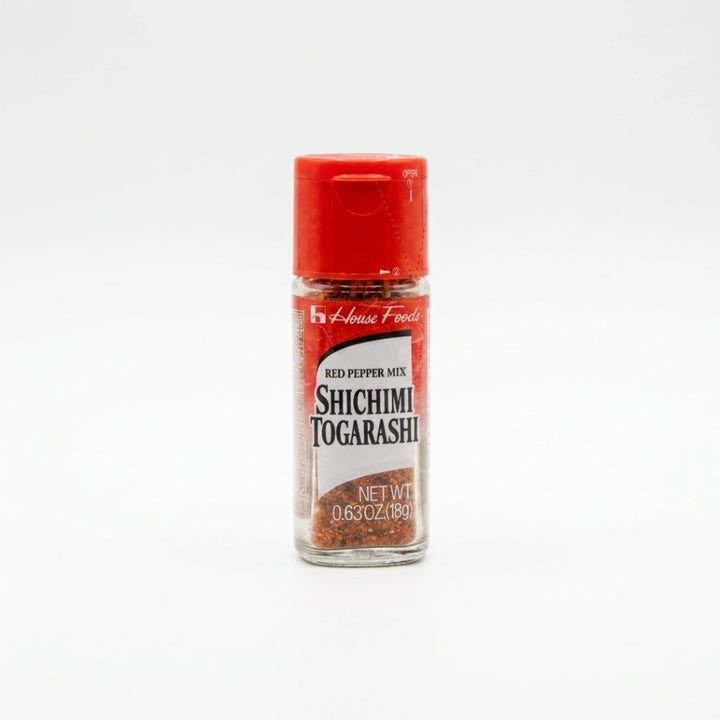 House Foods Shichimi Togarashi, eine japanische 7-Gewürz-Mischung, in einer transparenten Glasflasche mit rotem Streudeckel. Das scharfe Chilipulver ist für authentische asiatische Gerichte wie Ramen oder Sushi.