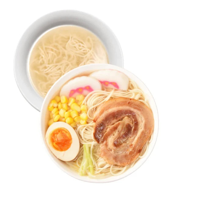 Zwei appetitliche Schalen japanischer Ramen: Die vordere zeigt goldgelbe Nudelsuppe mit saftigem Chashu-Schweinebauch, perfekt gekochtem Ei, Mais und bunten Narutomaki-Fischfrikadellen, ideal für Feinschmecker.