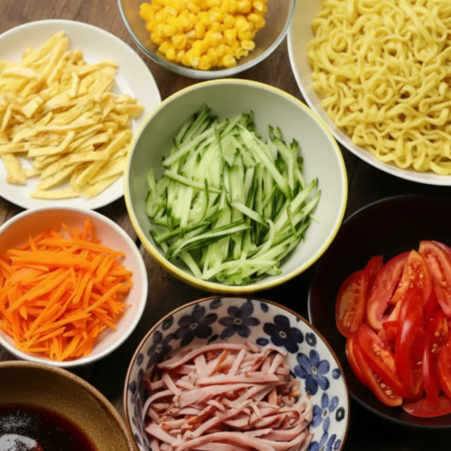 Vielfältige, frisch geschnittene Zutaten für einen asiatischen Nudelsalat, darunter gekochte Nudeln, feine Gurken-, Karotten- und Eierstreifen, sowie Tomatenspalten, Schinken und Mais, appetitlich in Schüsseln auf einem Holztisch arrangiert.