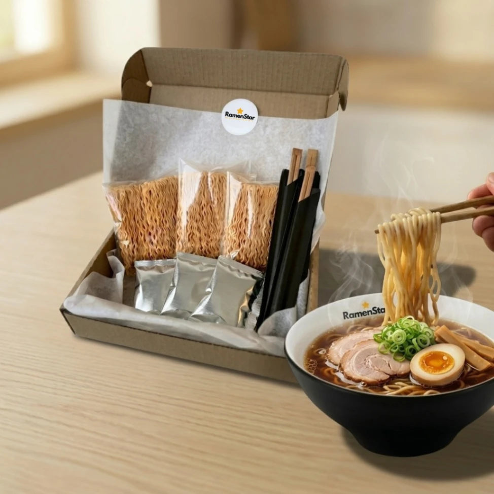 Ein geöffnetes RamenStar Kochbox-Set mit drei Packungen trockener Ramen-Nudeln, Soßenpäckchen und Essstäbchen. Daneben eine dampfende Schale fertiger Ramen mit Chashu, Ei und Frühlingszwiebeln, aus der Nudeln gehoben werden.