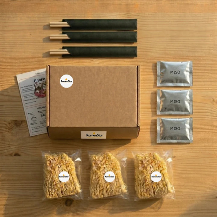 RamenStar Kochbox Set für Miso Ramen auf Holztisch, inklusive drei Portionen Instant-Nudeln, Miso-Pasten, Essstäbchen und Kochanleitung. Ideal für ein authentisches japanisches Gericht zu Hause.