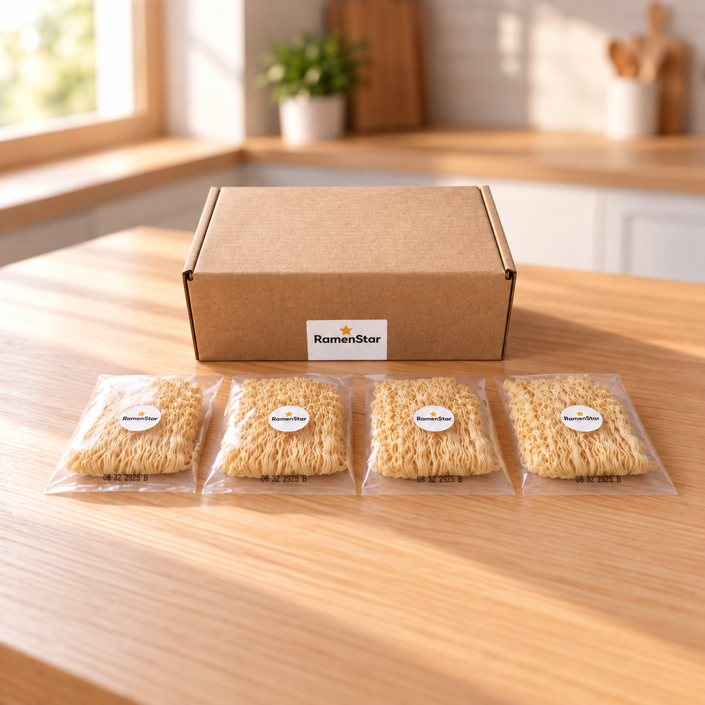 Brauner Versandkarton mit RamenStar-Logo und vier durchsichtigen Päckchen abgepackter Ramen-Nudeln auf einem hellen Holztisch.