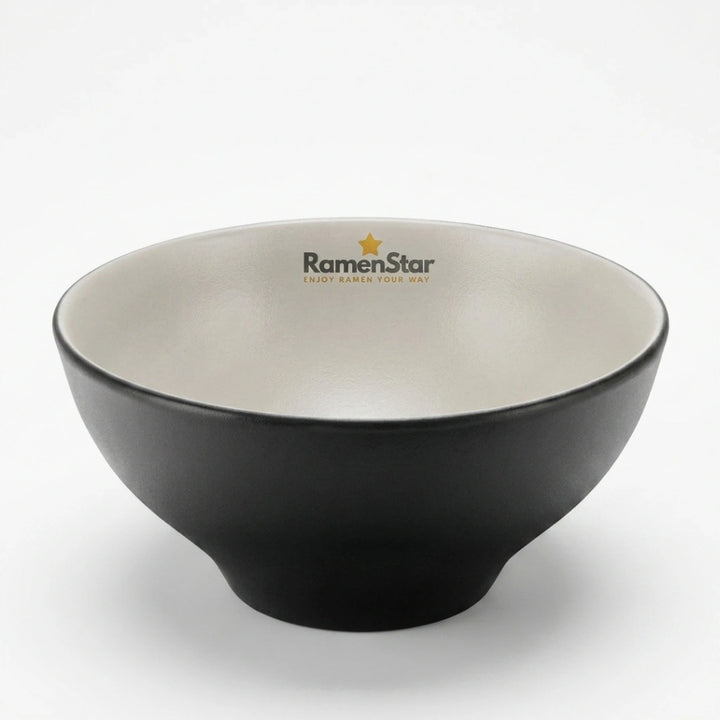 Eine stilvolle, matte schwarze Ramen-Schale von RamenStar, innen hellbeige, perfekt für authentischen Ramen-Genuss. Das Markenlogo mit goldenem Stern ziert den oberen Rand dieser hochwertigen japanischen Nudelschale.
