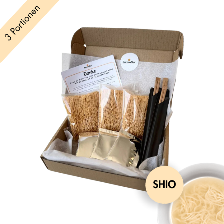 Abgebildet ist eine Probierbox von RamenStar mit drei Portionen Shio-Ramen in einer umweltfreundlichen Kartonverpackung. Die Inhalte – Nudeln, Suppenbasis und Stäbchen – sind ordentlich in Seidenpapier eingelegt, begleitet von einer Begrüßungskarte. Rechts unten weist ein runder Button mit „SHIO“ auf den enthaltenen Salzgeschmack hin. Die helle Brühe wirkt leicht und aromatisch.