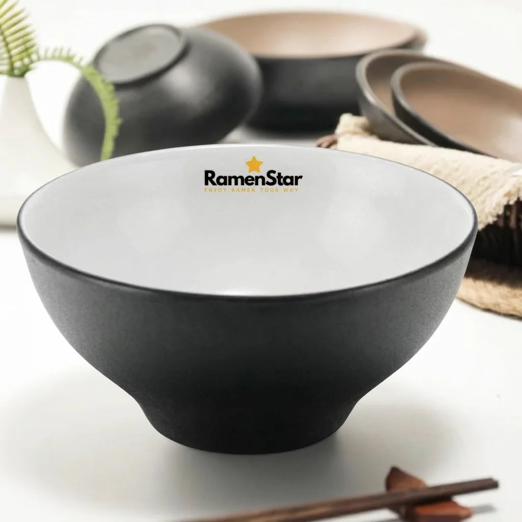 Eine stilvolle, matte schwarze Ramen-Schale von RamenStar, innen hellbeige, perfekt für authentischen Ramen-Genuss. Das Markenlogo mit goldenem Stern ziert den oberen Rand dieser hochwertigen japanischen Nudelschale.