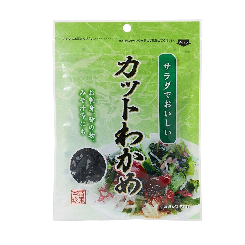 Transparente Verpackung mit getrockneten Wakame-Algen. Die Vorderseite zeigt den Produktnamen „カットわかめ“ in großen japanischen Schriftzeichen auf grünem Hintergrund. Links ist ein Sichtfenster mit dunklen Wakame-Stückchen, rechts ein Bild eines Salats mit Wakame und Gemüse. Text auf der Verpackung weist auf die Verwendung in Salaten, zu Sashimi, in Essiggerichten und Misosuppen hin.
