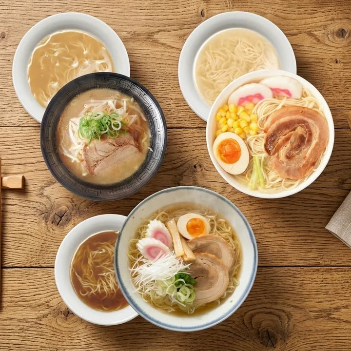Drei verschiedene Schalen Ramen und zugehörige Schalen mit Brühe und Nudeln, auf einem Holztisch von oben gesehen. Eine dunkle Schale enthält Ramen mit cremiger Brühe, Chashu-Schweinefleisch, Sojasprossen und Frühlingszwiebeln. Eine weiße Schale zeigt Ramen mit heller Brühe, Chashu, halbiertem weichgekochtem Ei, Mais, rosa-weißen Narutomaki-Fischkuchen und Grüngemüse. Eine weitere weiße Schale mit blauem Rand enthält Ramen mit klarer Brühe, Chashu, halbiertem weichgekochtem Ei, Narutomaki, Bambussprossen.